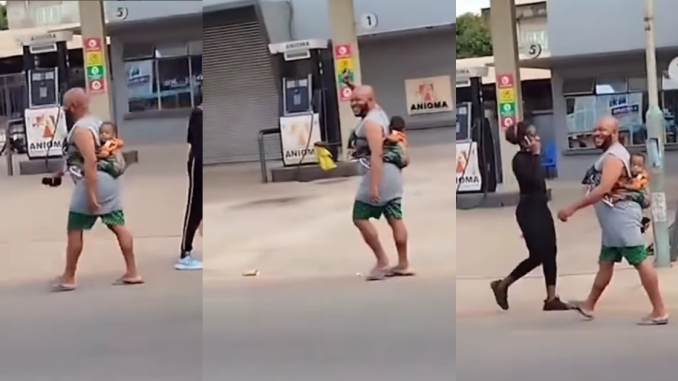 "Husband material" – Man spotted joyfully strolling with a child on his back in Onitsha (WATCH)