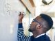 Cropped shot of a young man writing on a whiteboard in a classroom