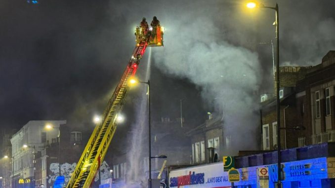 Flames engulf block of flats sending smoke billowing into sky as 100 firefighters rush to tackle inferno