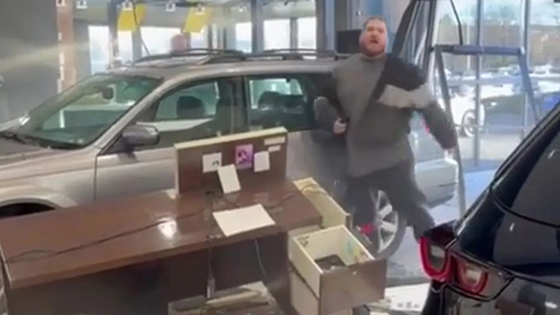 Watch moment raging driver smashes brand new car through dealership window while furiously demanding a refund